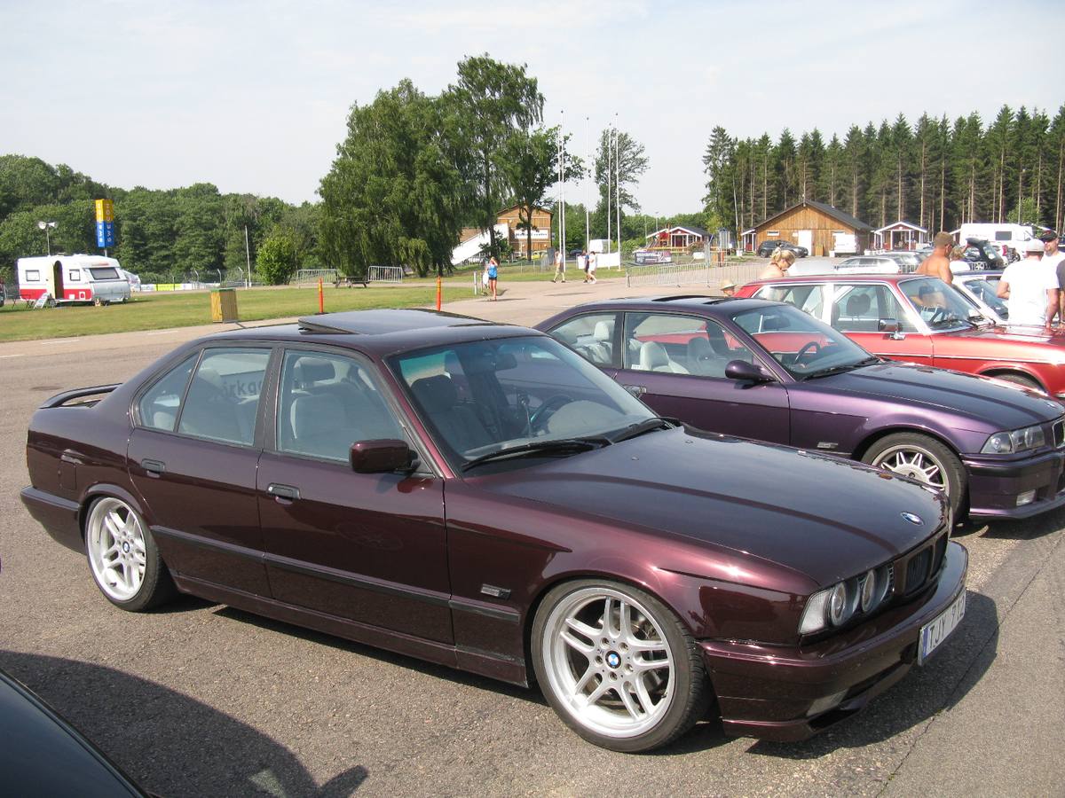 Tmavě vínový sedan BMW řady E34 zaparkovaný na srazu