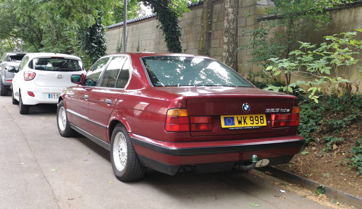 Vínově červené BMW 525tds řady E34 zaparkované u zdi