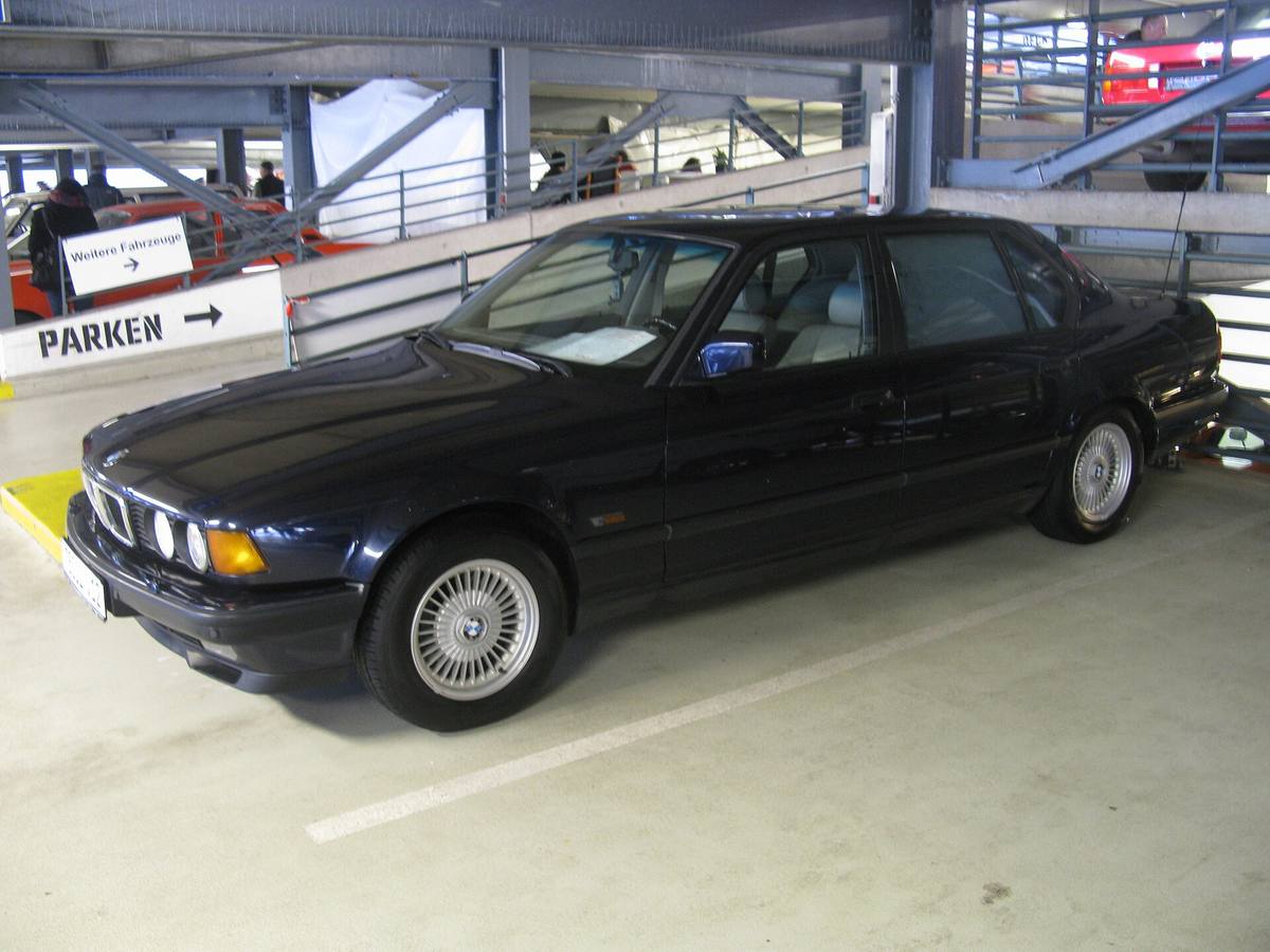 Tmavě modré BMW 750iL generace E32 z boku na parkovišti