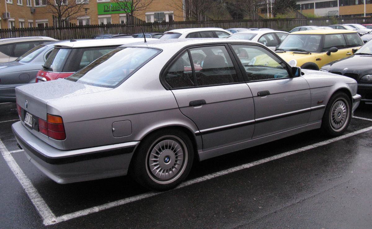 Tmavé BMW 540i řady E34 se šestistupňovou převodovkou zaparkované na ulici