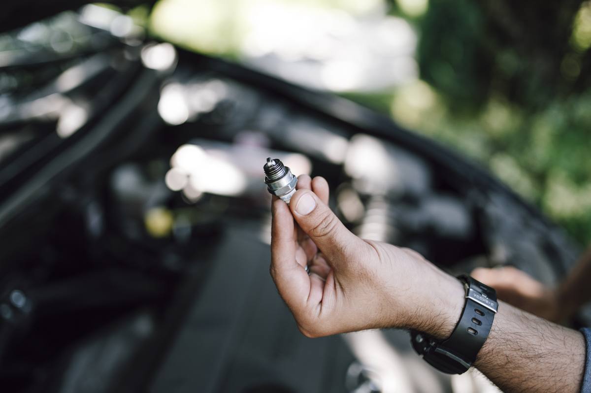 Ruka mechanika vytahuje vstřikovací ventil z palivové lišty motoru