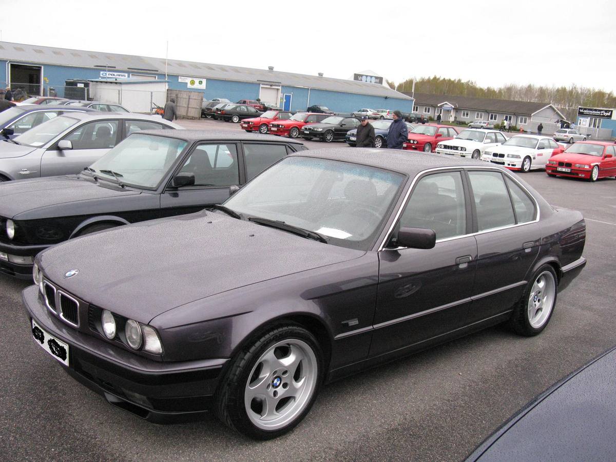 Tmavě fialové BMW 540i řady E34 na parkovišti při setkání příznivců značky
