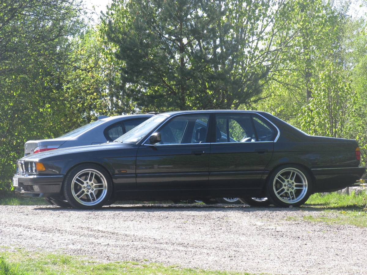 Tmavá sedmička BMW řady E32 z boku na štěrkovém parkovišti