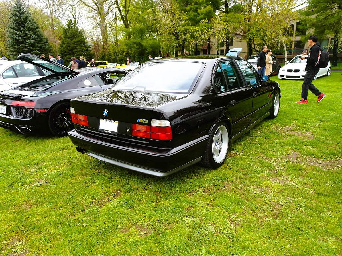 Černé BMW M5 řady E34 zezadu, pod zadním nárazníkem světlá zástěrka