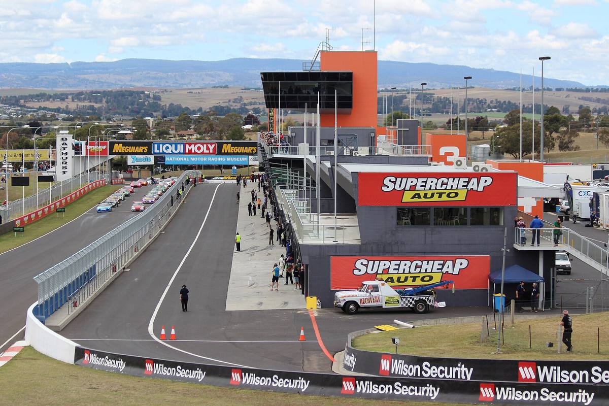 Cílová rovinka a boxová ulička okruhu Mount Panorama v Bathurstu, za nimi kopce a město