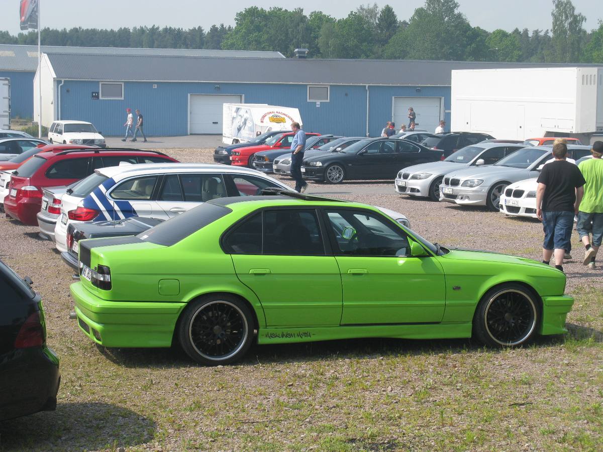 Bok zeleného sedanu BMW řady 5 generace E34 s vnějším zrcátkem na pravé straně