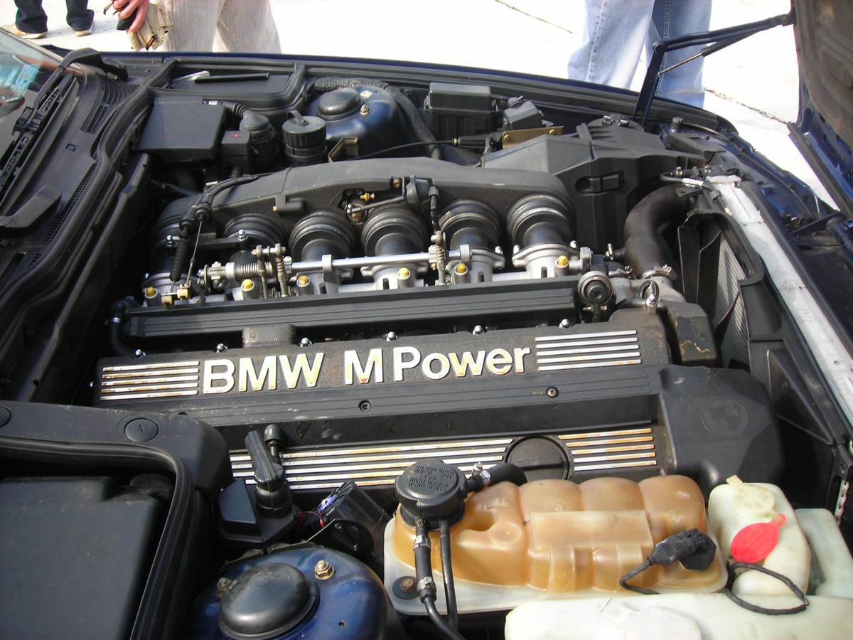 Otevřený motorový prostor BMW M5 řady E34 s šestiválcem S38, víko ventilů s nápisem BMW M Power a uzávěrem plnicího hrdla oleje