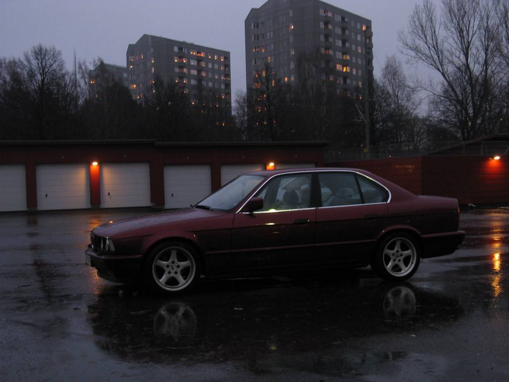 Sedan BMW řady E34 na mokrém parkovišti za šera