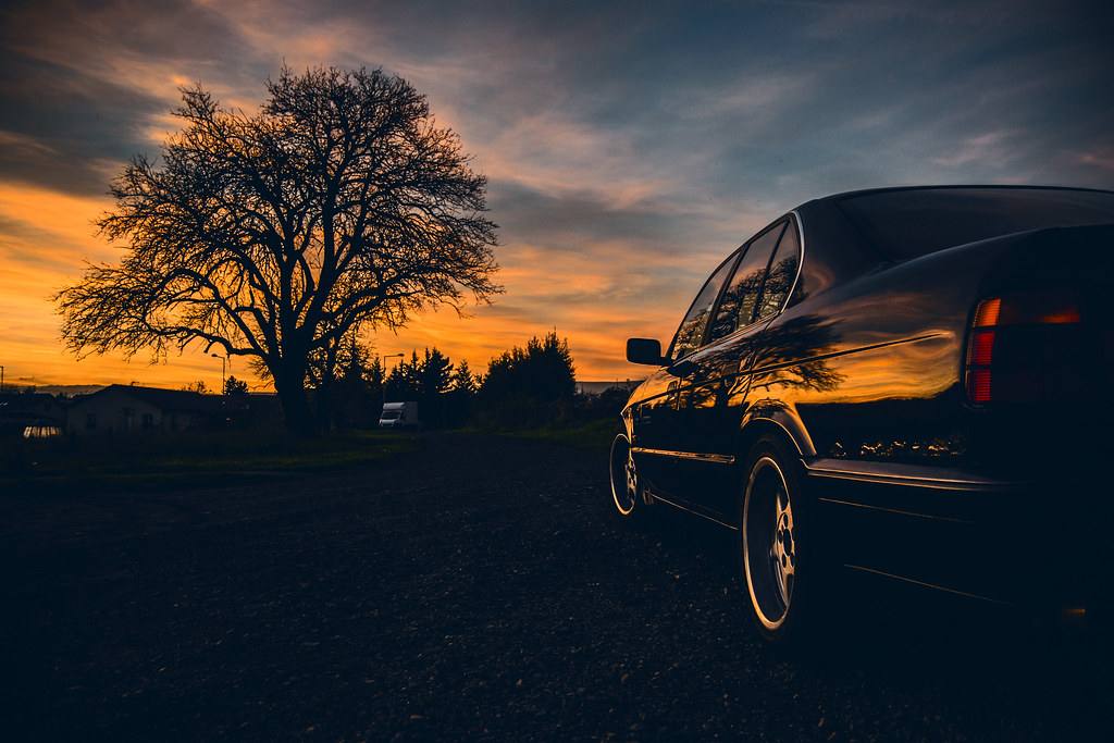 Bok a záď sedanu BMW řady E34 proti večerní obloze