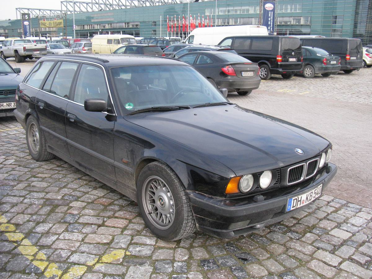 Černé kombi BMW řady E34 zaparkované na dlažbě