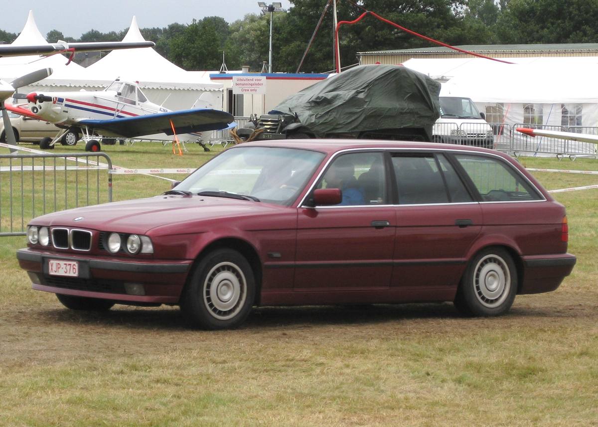 Vínově červené BMW řady 5 E34 Touring na travnaté ploše letiště