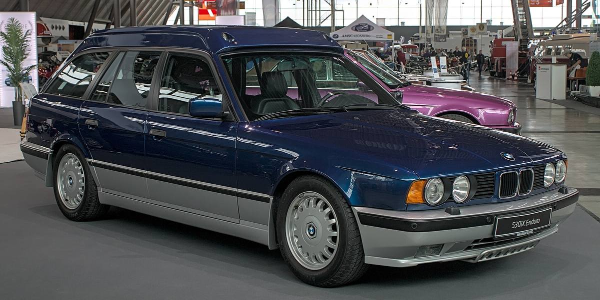 Tmavě modré kombi BMW 530iX Enduro se zvýšenou střechou ve výstavní hale