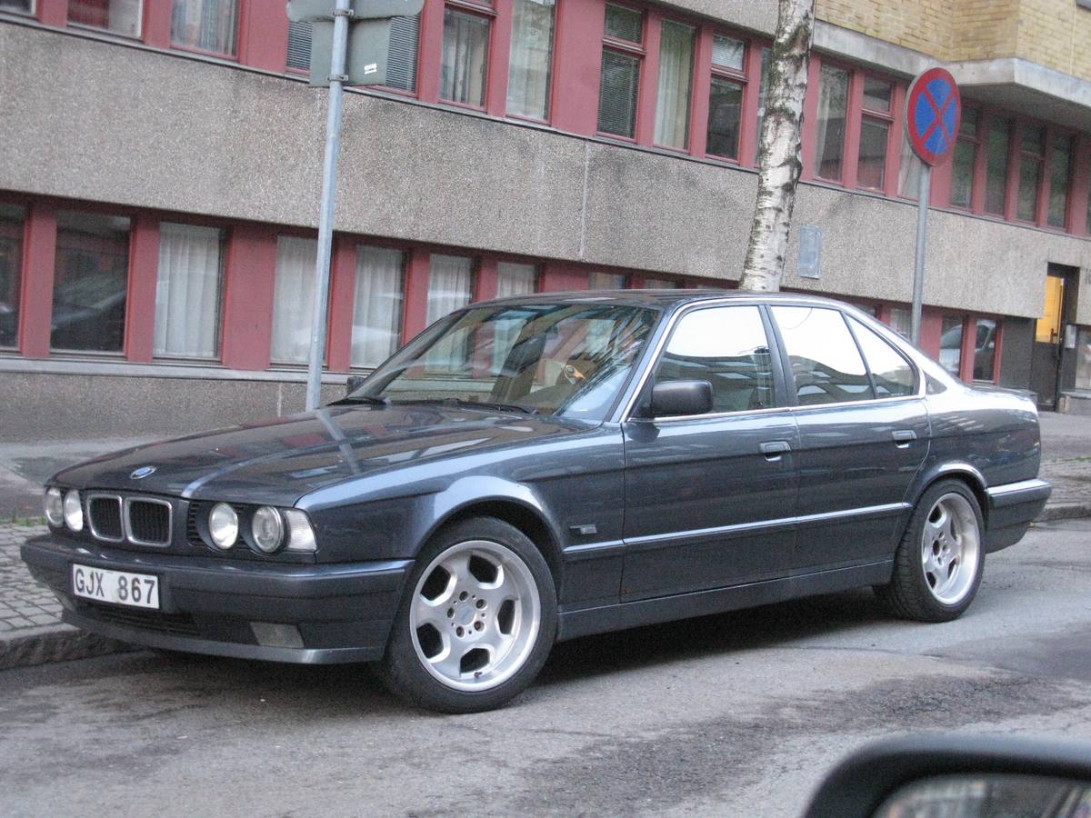 Sedan BMW 525i z řady E34 zaparkovaný u chodníku