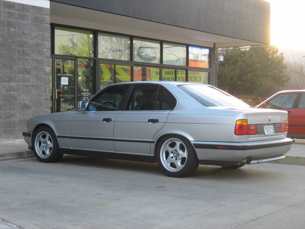 Stříbrné BMW M5 z řady E34 zaparkované na ulici